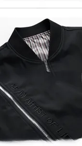 Detail showing the ribbed neckline, Vogue zipper, and artistic embroidery on black jacket