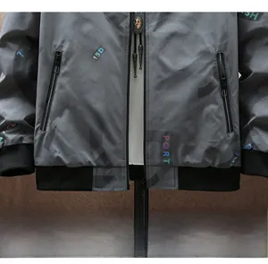 Detail der grauen Bomberjacke mit Verlaufsbuchstabenmuster und Metall-Pferdeanhänger