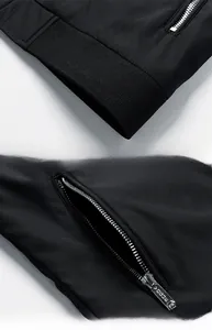 Detail view of the ribbed knit hem and metallic zipper pocket on black men's jacket