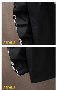 Detailed macro view showing metal snap buttons and black and white checkerboard pattern sleeves