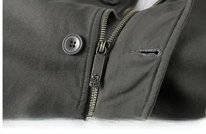 Detail shot of heavy-duty metal zipper and resin button on green canvas jacket