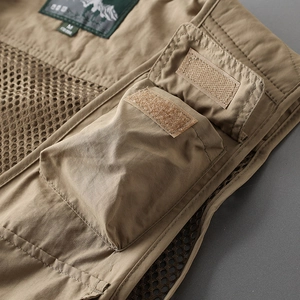 Detail of khaki tactical vest featuring cargo pockets with velcro and brand neck label