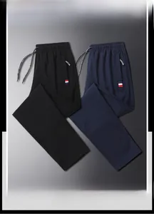 Detail view of men's casual trousers with drawstring waist and zip pockets in black and navy