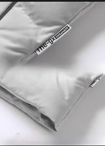 Detail view of the woven label and double-stitched hem on the light gray padded vest jacket
