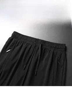 Detail of elastic waist with drawstring and zipper pocket on black ice silk pants