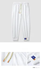 Detail view of white jogger pants with colorful drawstrings and a woven brand label
