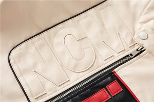 Close-up of NCM embossed patch on beige faux leather jacket with red and black stripes