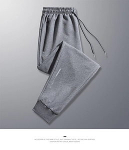Detail of grey joggers featuring drawstring waist, zipper pockets and reflective ankle branding
