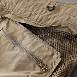 Detail of khaki outdoor vest showing metal zipper, breathable mesh lining and D-ring