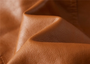 Detailed macro shot of brown leather fabric showing premium lychee texture and matte finish