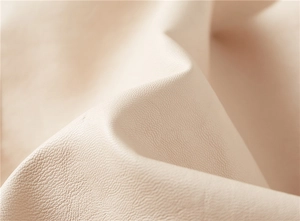 Macro shot of high-quality beige faux leather texture with soft natural grain and folds