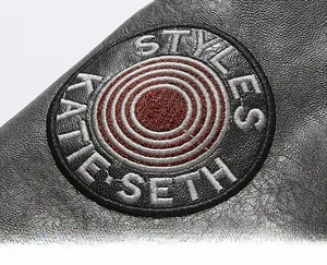 Detailed close-up of premium black lychee-textured leather with circular embroidery badge