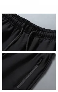 Detail view of black sweatpants featuring elastic drawstring waist and side zipper pocket