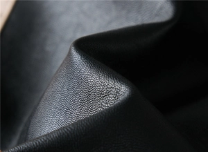Macro close-up of premium black leather jacket material with fine pebble grain texture