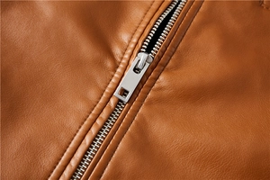 Detailed macro view of silver metal zipper and lychee texture on brown PU leather jacket