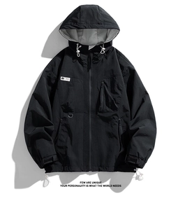 Detail of black windbreaker featuring hood drawstrings and tactical letter patches