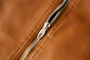 Detailaufnahme einer braunen PU-Lederjacke mit feiner Textur und silbernem Reißverschluss