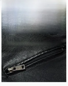 Gros plan détaillé d'une veste en cuir PU noir montrant la texture de la poche zippée