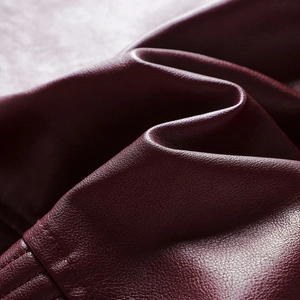 Dettaglio della texture in pelle PU bordeaux con grana litchi e cuciture precise sulla giacca