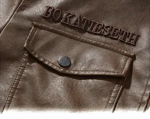 Detail of dark brown leather jacket featuring flap pocket and BOKATIESETH embroidery