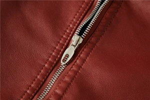 Detailed close-up of premium metal zipper on a wine red leather jacket with grain texture
