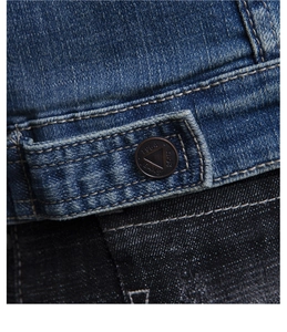 Macro shot of 1964 JEANS metal button and bronze rivets on a deep blue denim jacket