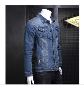 Detail of blue denim jacket showing side seam yellow woven label and metal buttons