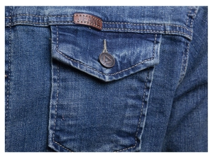 Detail of a denim jacket pocket with leather patch and a vintage metal button