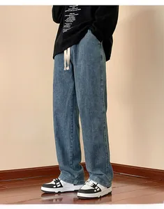 Detail of dark blue straight-leg jeans featuring a white drawstring waist and washed texture