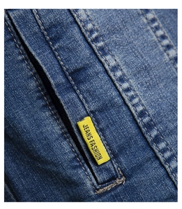 Close-up of durable denim stitching and yellow fashion label on blue denim jacket