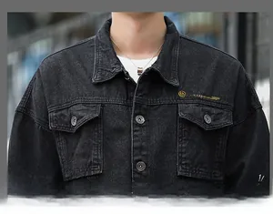 Dettaglio della giacca di jeans nera con bottoni metallici e ricamo giallo sulla tasca