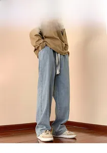 Detail of light blue wide-leg vintage wash jeans with a cotton drawstring waistband