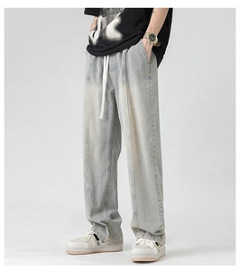 Detail view of light blue washed men's wide-leg jeans with drawstring waist and middle seam