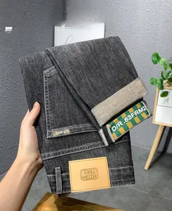 Vue détaillée du jean en denim gris foncé avec revers à ruban tissé à carreaux sur les ourlets