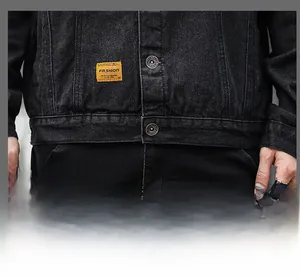 Dettaglio della tasca della giacca di jeans grigio scuro con etichetta gialla e bottone