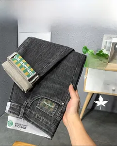 Détail de jeans gris foncé avec bordure en ruban à carreaux jaune-vert sur les poches