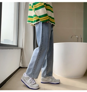Detail view of light blue straight-leg jeans with washed denim texture in a casual street style
