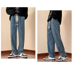 Detail view of light blue denim jeans showing elastic drawstring waist and washed texture