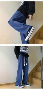 Detail view of mid-blue loose jeans with white drawstring waist and X embroidery