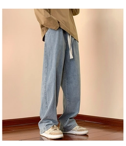 Detail of light blue wide-leg jeans with vintage wash and adjustable white drawstring waist
