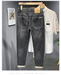 Détail d'un jean slim gris foncé avec un patch en cuir marron et un ourlet replié stylé