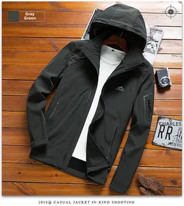 Detail of grey-green hooded outdoor jacket featuring sleeve pocket and outdoor embroidery