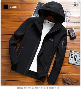Flat lay of black hooded outdoor jacket with chest logo on a rustic wooden background