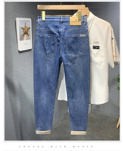 Détail d'un jean slim délavé bleu avec écusson en cuir marron et étiquette métallique