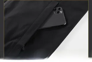 Detail of a functional black jacket showing a concealed zipper pocket with a smartphone inside