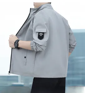 Detail of light grey outdoor sports jacket sleeve with functional pocket and logo label