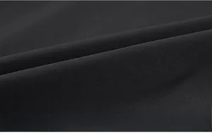 Close-up of black fine-textured fabric showing the dense weave and soft drape of the jacket