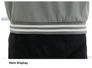 Close-up of the ribbed hem with white double stripes on a sage green baseball jacket