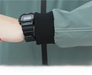 Macro shot of gray-green casual jacket sleeve with black elastic ribbed cuffs and white stitching