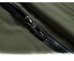 Detail of smooth metal zipper and textured olive green twill fabric on the windbreaker